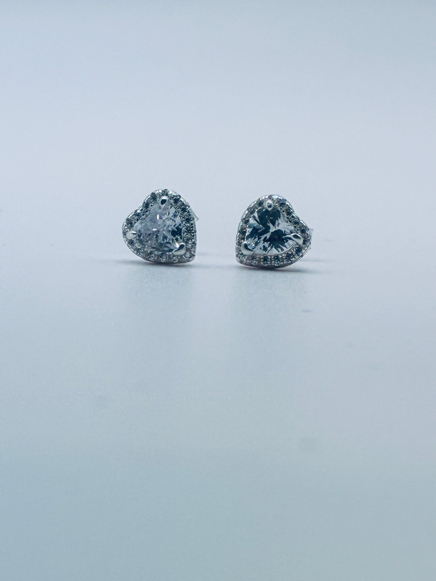 Heart-shaped diamond earrings on a light gray background