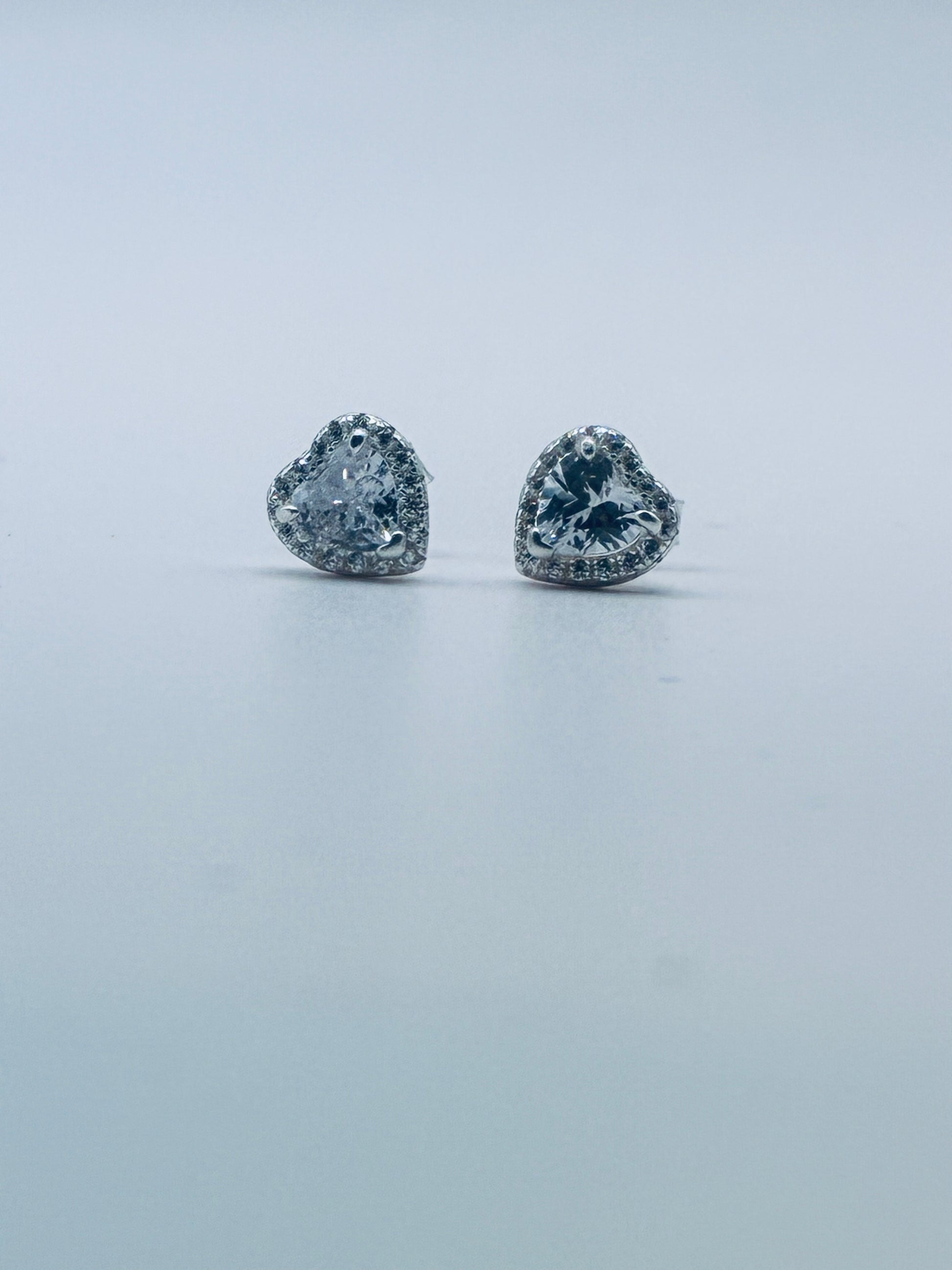Heart-shaped diamond earrings on a light gray background